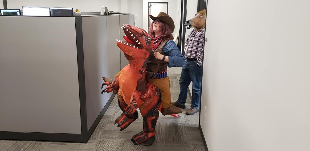 A majestic picture of a cowgirl riding a dinosaur, standing by a man wearing a horse head mask.